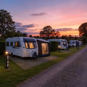 Peaceful UK caravan site with touring caravans relaxing on fully serviced pitches during an evening stay