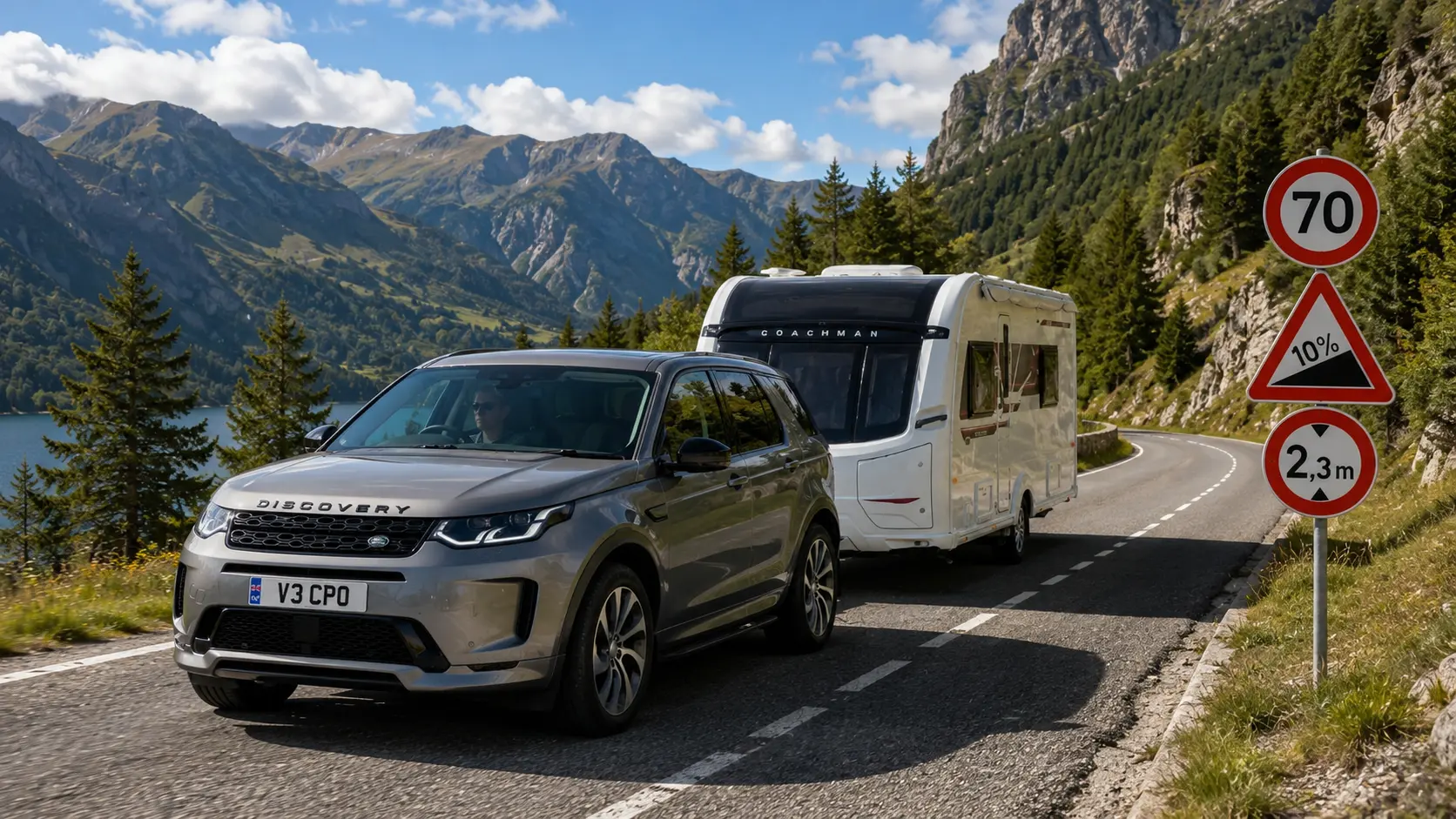 Silver Land Rover Discovery towing a Coachman caravan on a scenic European mountain road with important road signs
