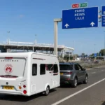 Silver Land Rover Discovery towing a Coachman Sussex Singleton caravan away from LeShuttle towards the French motorway network