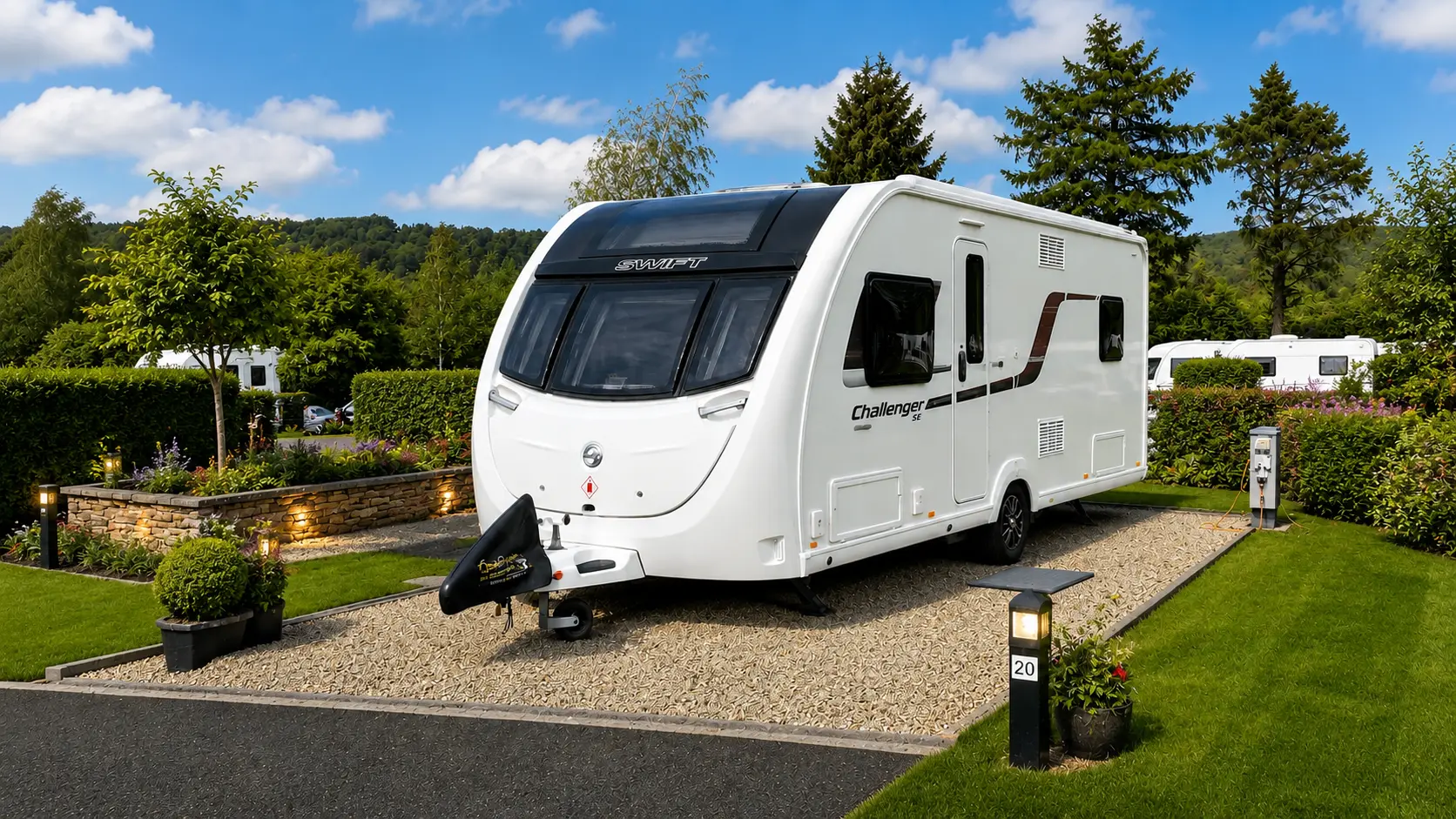 Modern touring caravan on a landscaped luxury pitch at a UK campsite with manicured lawns and premium surroundings