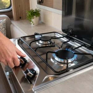 Adult hand safely igniting a gas hob in a modern UK touring caravan kitchen